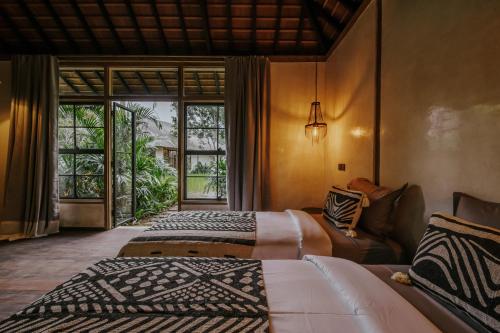 a bedroom with two beds and a couch and a window at Bedulu Cliff Estate Villas Complex Ubud in Ubud