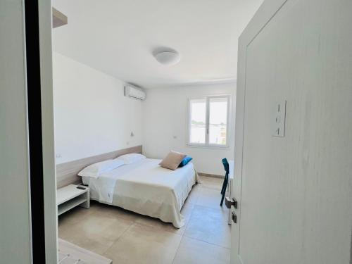 a white bedroom with a bed and a window at Verde Blu Vacanze B&B in Torre Lapillo