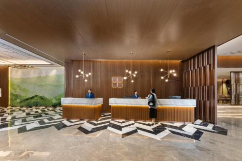 a lobby with a reception desk with people in it at Hilton Garden Inn Huzhou High-Speed Railway Station in Huzhou