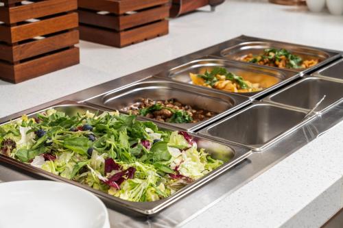 a buffet with three trays of food on a counter at Hilton Garden Inn Huzhou High-Speed Railway Station in Huzhou