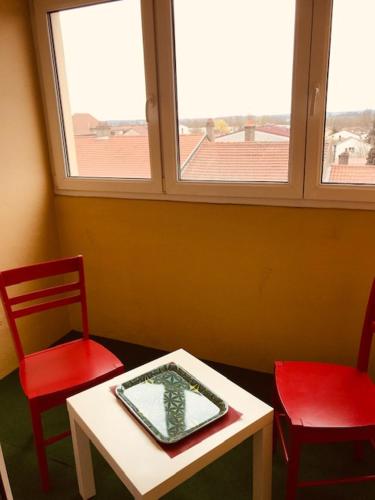 une chambre avec deux chaises rouges et une table avec un miroir dans l'établissement Le Léonie, à Hagondange