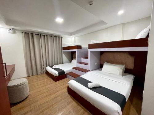 ein Hotelzimmer mit 2 Betten und einem Stuhl in der Unterkunft Staycation Hotel 