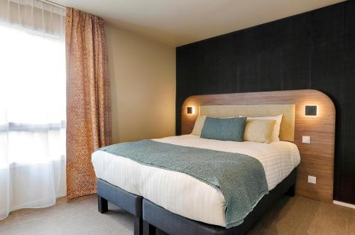 a bedroom with a large bed and a large window at Résidence Meublée Bellini Vannes in Vannes