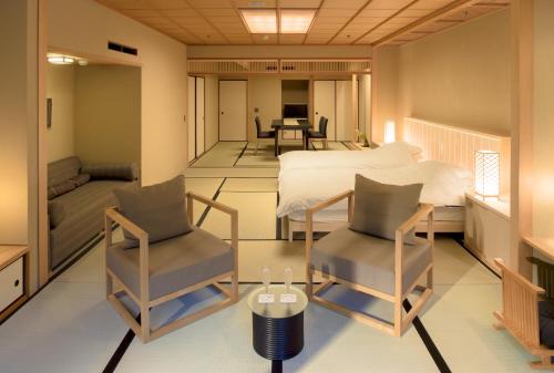 a bedroom with a bed and two chairs and a table at Gora Kadan in Hakone