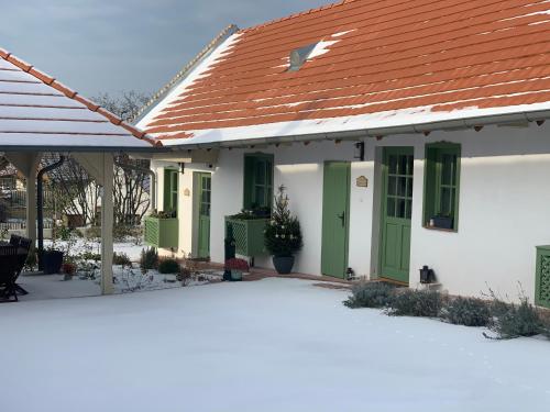 a white house with green doors and a red roof at Pannonhalma Várlak Vendégház in Pannonhalma
