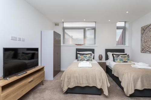 a bedroom with two beds and a flat screen tv at Studio Flat in the Heart of Crawley- Apartment 5 in Crawley