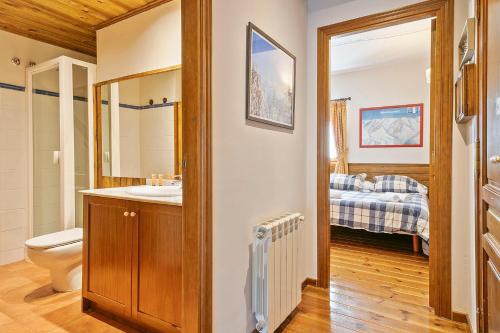 a bathroom with a sink and a toilet and a bedroom at Baqueira Apartamentos Cota 1700 a pie de pistas in Baqueira-Beret