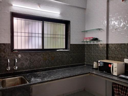 uma cozinha com um lavatório e uma janela em Katke's HomeStay. em Sholapur
