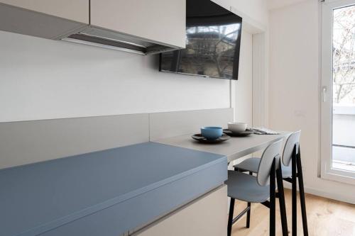 uma cozinha com um balcão azul e cadeiras em Casa Kaleido em Trento