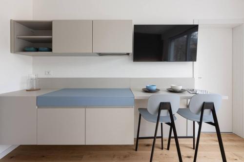 uma cozinha com armários brancos e um balcão azul em Casa Kaleido em Trento