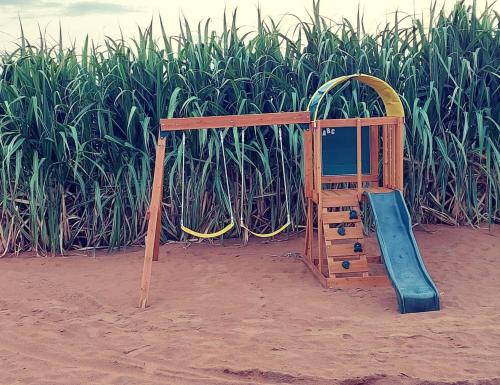 a playground with a slide in front of a cornfield at My Resort in Al Rahba
