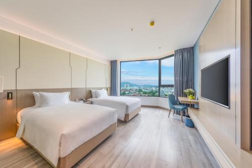 a hotel room with two beds and a flat screen tv at Awaken Da Nang Hotel in Da Nang