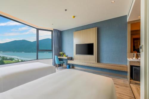 a bedroom with a large bed and a tv at Awaken Da Nang Hotel in Da Nang