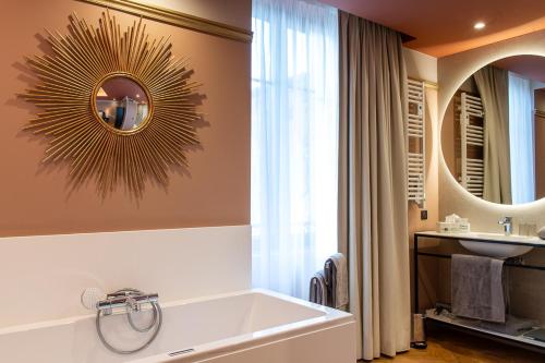 a bathroom with a large tub and a mirror at Hôtel Restaurant Vaillant proche Europapark Rulantica in Sélestat
