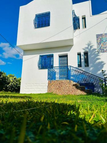a white building with blue balconies on it at Dar louzir à Tazarka in Tazarka