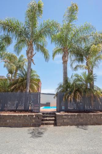 a fence with palm trees in front of a pool at Pioneer Station Motor Inn in Swan Hill