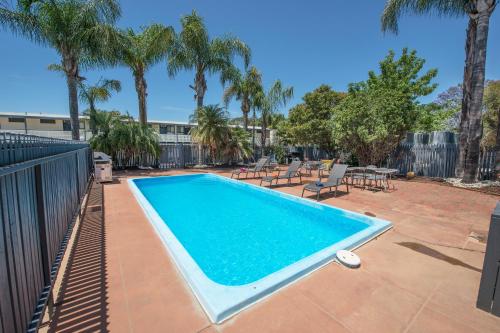 a swimming pool in a yard with palm trees at Pioneer Station Motor Inn in Swan Hill