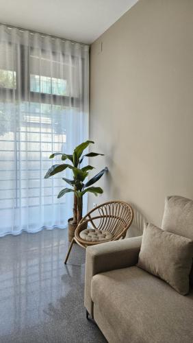 uma sala de estar com um sofá e uma planta em Imperial Apartamentos Puerto em Valência