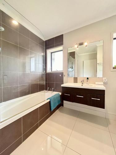 a bathroom with a tub and a sink and a mirror at Rotorua 5 Bedrooms 3 bathroom family house in Rotorua