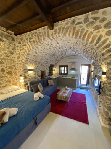 1 dormitorio con cama y pared de piedra en Indigo Leonidion, en Leonidio