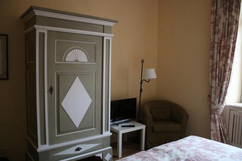 a bedroom with a bed and a cabinet with a monitor at Hotel Schloss & Gut Ulrichshusen in Ulrichshusen