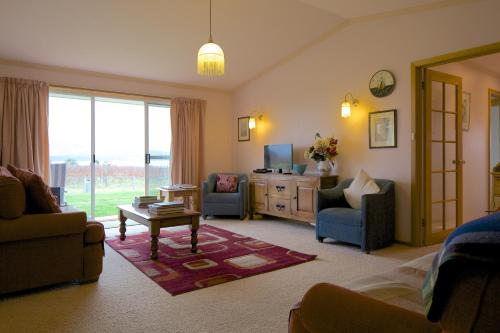 a living room with a couch and chairs and a tv at Riversdale Estate Cottages in Cambridge