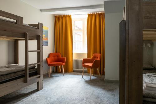 a bedroom with two bunk beds and two orange chairs at STF Hostel Stigbergsliden in Gothenburg