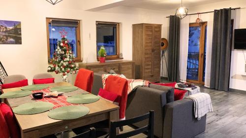 a dining room with a table and a christmas tree at Apartamenty Dwupoziomowe Na Dwa Widoki z Jacuzzi & Sauna in Zakopane