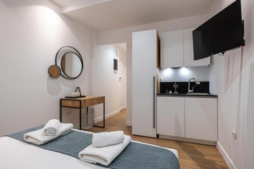 a white bedroom with a bed and a kitchen at Kriel Suites by LIV Homes in Athens