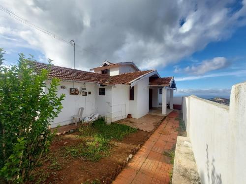 a white house with a fence in front of it at VERMONT HOMe STAY in Ooty