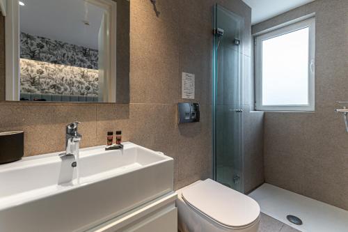 a bathroom with a sink and a toilet and a shower at Kriel Suites by LIV Homes in Athens
