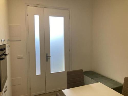 uma porta num quarto com uma mesa e cadeiras em Appartamento a 200 mt dal mare em Lido di Jesolo