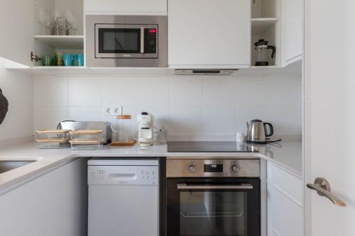 a white kitchen with a stove and a microwave at Feel Welcome Barcelona # SPLAU in Cornellà de Llobregat