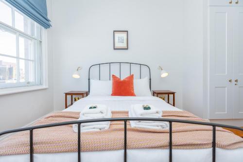 倫敦的住宿－Bright 1BR Apt, 1min to Tube & Kensington Gardens，白色卧室配有带橙色枕头的床