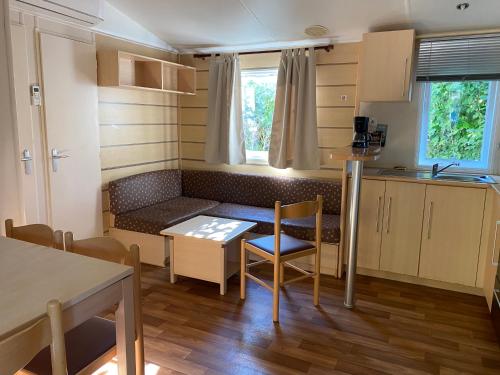 une petite cuisine et salle à manger avec une table et des chaises dans l'établissement Mobil-home 3 chambres, à Angicourt