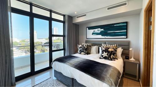 um quarto com uma cama grande e uma janela grande em Pearls Apartments - Sea Facing em Durban