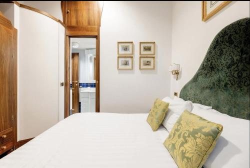a bedroom with a white bed with a green headboard at Pantheon Antique Suite in Rome
