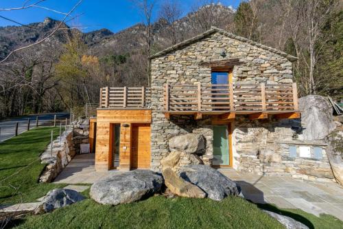 a stone house with a balcony and some rocks at Bel Sass in Piuro