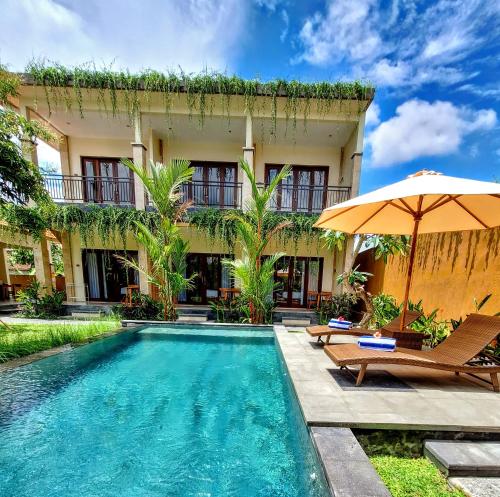 a house with a swimming pool and an umbrella at tiny's house in Ubud