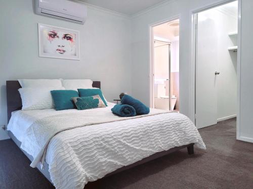 una camera da letto con un grande letto bianco con cuscini blu di Home away from home a Melton