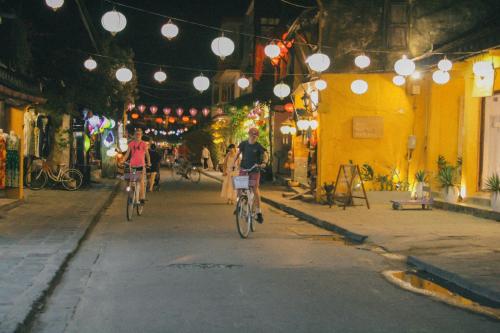 a group of people riding bikes down a street at LA GAI HOMESTAY HOI AN in Hoi An