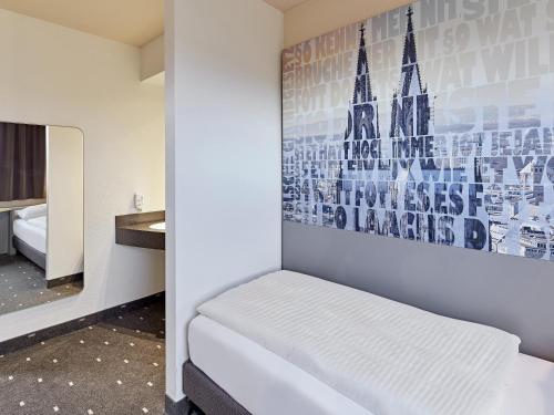 a room with a bed and a painting on the wall at B&B Hotel Köln-West in Cologne