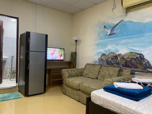 a living room with a couch and a refrigerator at Backpackers Place - Central Bus Terminal in Abu Dhabi