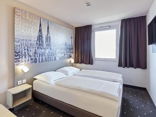 a bedroom with two beds and a picture on the wall at B&B Hotel Köln-West in Cologne