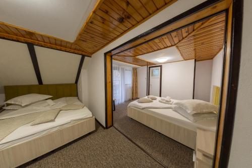 two beds in a room with a mirror at Camere de închiriat Larisa in Moieciu de Sus
