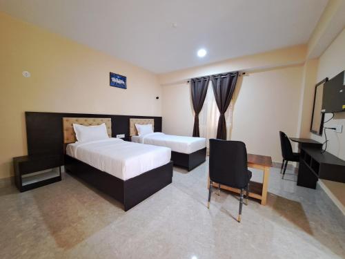 1 dormitorio con 2 camas, escritorio y TV en snow white retreat hotel and restaurant en Gangtok