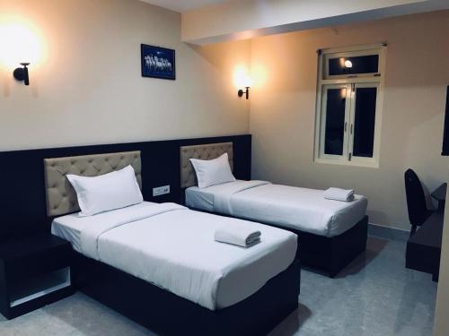 ein Hotelzimmer mit 2 Betten und einem Fenster in der Unterkunft snow white retreat hotel and restaurant in Gangtok