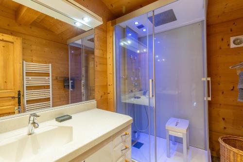 a bathroom with a glass shower and a sink at Chalet Coelacanthe in La Clusaz