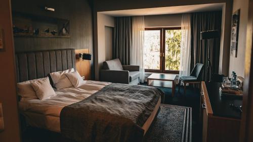 Habitación de hotel con cama, silla y ventana en Hotel & Medi-Spa Biały Kamień, en Świeradów-Zdrój