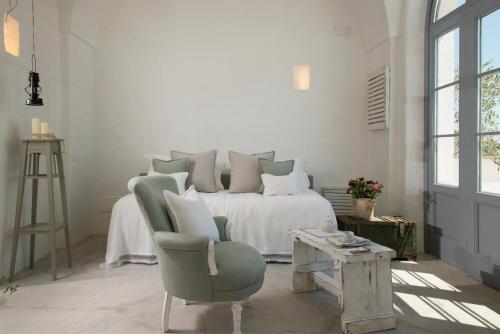 a white bedroom with a bed and a chair at Masseria Le Torri in Polignano a Mare